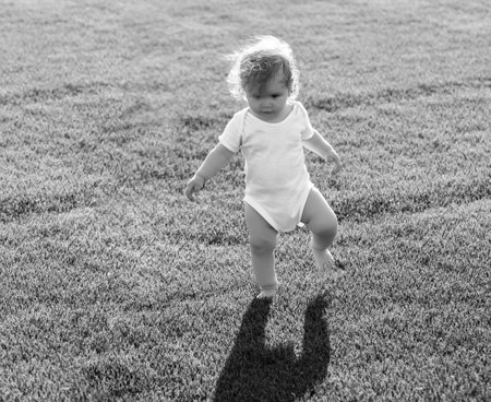 First step. Baby bare legs standing on green grass.の写真素材
