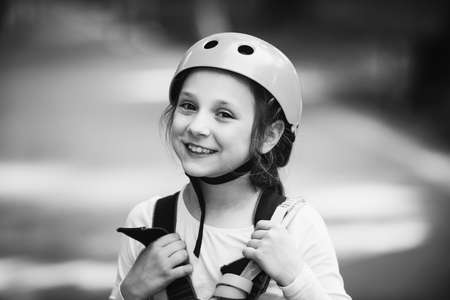 Little girl climbing in adventure activity park with helmet and safety equipment. Little girl...