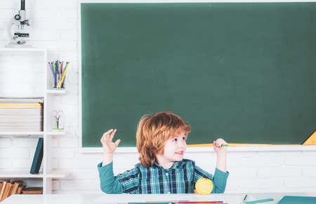 Child near chalkboard in school classroom. Happy school kids at lesson. School education and people concept - cute pupil over blackboard background.の写真素材