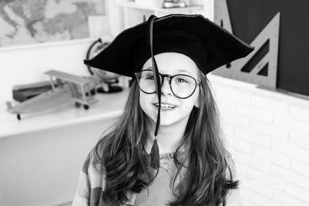 Funny little student girl in graduation cap. Child from elementary school. Junior School.