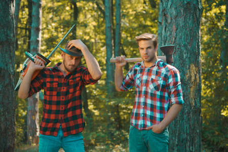 Man woodcutter holding ax. Axe in lumberjack hands cutting wood. Lumberman with a chainsaw in forest. Concept of a professional logging woodcut.の写真素材