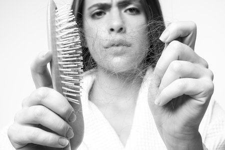 Sad girl with damaged hair. Hair loss problem treatment. Portrait of woman with a comb and problem hair.の写真素材