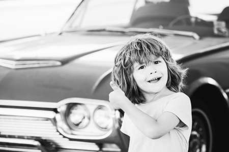 Kid refuel the car. Gas station. Happy boy against red retro automobile.の写真素材