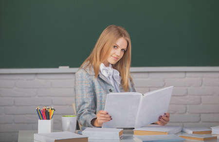 Female student holding book on lesson lecture in classroom at high school or college.