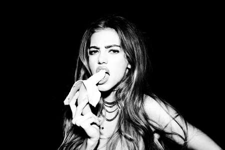 Portrait of seductive young woman eating banana. Tropical fruits. Summer concept. Healthy eating....