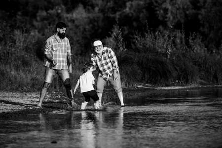 Three generation family. Skipping Stones with Dad adn Granddad. Three different generations ages: grandfather father and child son together.の写真素材