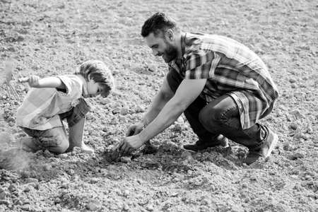 Father and son work on earth ground. Family planting. Daddy teaching little boy to do gardening.の写真素材