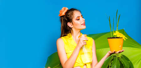 Spring and hobbies. Girl model planting flowers in pot. Planting flowers on blue background isolated. Banner spring design, advertising for website header.の写真素材