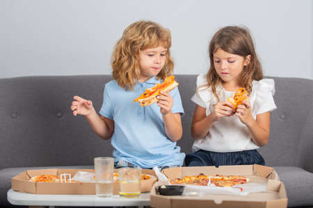 Happy daughter and son eating pizza. Children kids, little girl and boy eat pizza.の写真素材