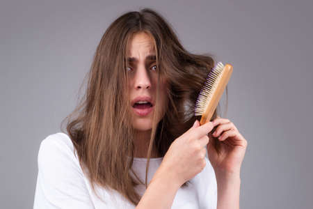 Young woman is very upset because of hair loss. Haircut and healthy haircare. Serious hair loss...