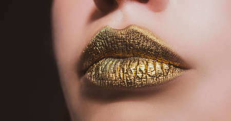 Golden lips. Woman sexy lip makeup isolated on black backgroundの写真素材