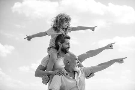 Father and son with grandfather was excited with pointing finger. Hand gestures point. Three generations of men having fun together outdoor.の写真素材