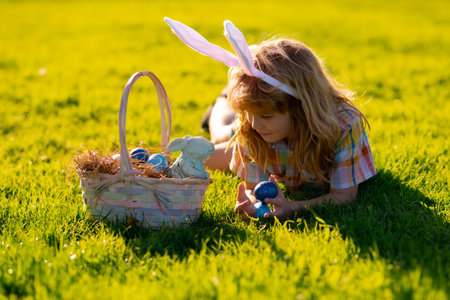 Child boy hunting easter eggs. Cute kid in rabbit costume with bunny ears having easter in park....