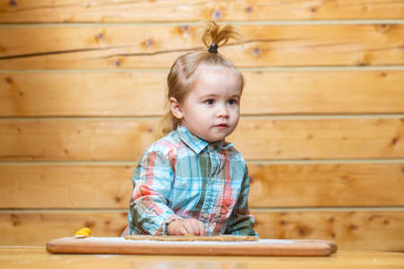 Childrens cook. Little child at kitchen cooking and playing with flour. Baby food, family breakfasts, child plays with kitchen utensils.の写真素材