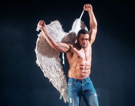 Muscle strong beautiful stripped male angel. Handsome young athletic man with a bare torso looks like an angel with white wings. Valentines day.の写真素材