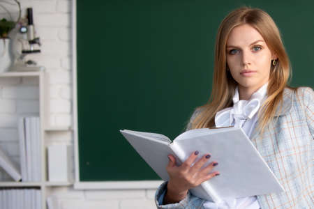 Close up portrait of young female college student studying in classroom on class with blackboard background.の写真素材