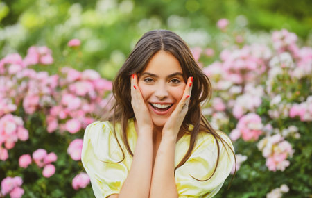 Spring woman smiling in rose garden outdoors. Natural beauty girl enjoy summer recreation.の写真素材