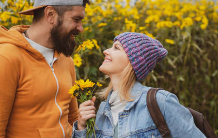 Young couple in love spends time together in autumn park with flovers. Man embracing and going to kiss sensual woman.の写真素材