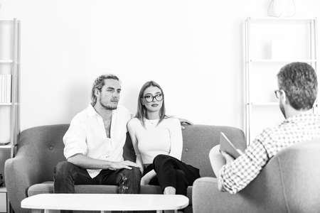 Social worker psychologist talking to young couple. Family at psychology session.の写真素材