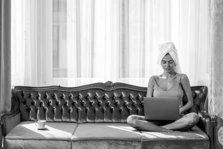 Beautiful sensual young woman in pajama using laptop enjoying morning leisure time in bedroom at home.の写真素材