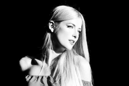 Portrait of elegant blonde woman with light on a black background. Beautiful female face in the darkness.の写真素材