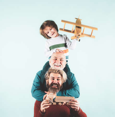 Man family. Father grandfather and son isolated on blue. Kid boy with toy airplane. Men family generation. Happy three age men family, old grandfather young adult grown son father and child.の写真素材
