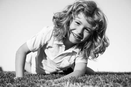 Portraits of happy kids playing and laying on grass outdoors in summer park.