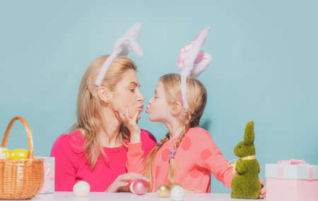 Mother and child daughter on Easter. Family celebrate Easter. Girls with bunny ears kiss, isolated on blue.の写真素材