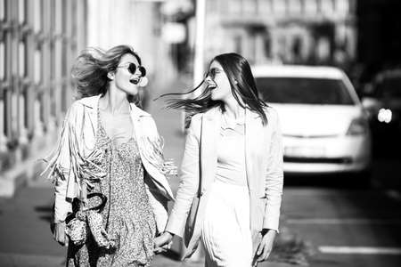 Two launching youngs women with sunglasses walking in the city. Funny vacation, romantic travel.の写真素材