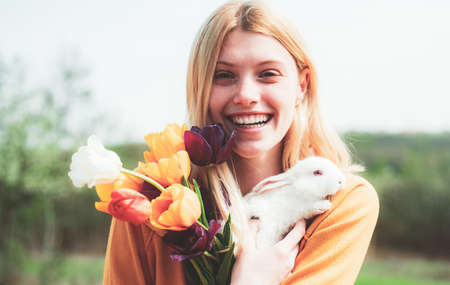 Easter Bunny. Beautiful young woman with bunny rabbit on farm.の写真素材