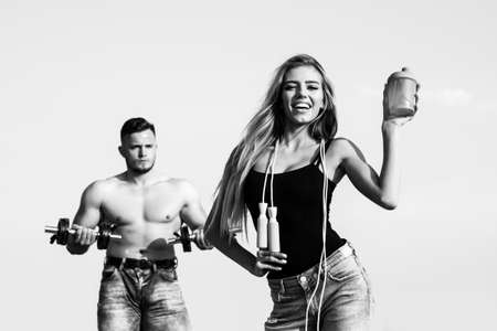 Slim female trainer of fitness with protein shaker. Man and girl with protein shake bottle and skipping rope. Smiling young woman and personal couple coach.の写真素材