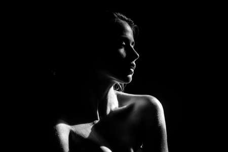 Tender girl, tenderness. Elegant young woman posing over black background. Light and shadow. Portrait of a beauty woman face.の写真素材
