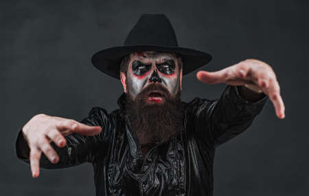 Man posing with Pumpkin. Scary Halloween man in hat - studio shot close-up. Fantasy horror Halloween. Scary face. Horror.の写真素材
