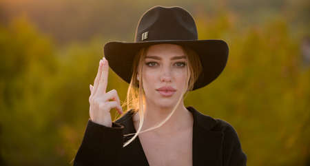 Girl holds hands like a gun. Spring romantic casual woman portrait. Beautiful western girl outdoor,...
