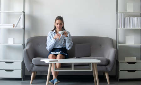 Young business woman freelancer or ceo employee with cup of coffee working in office.の写真素材