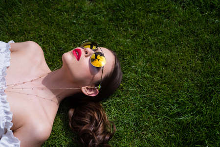 Portrait of young woman in sunglasses outdoor on grass. Romantic girl with beauty face.