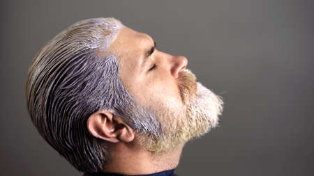 Stylist with hair dye and brush coloring hair at salon. Hair coloring man. Professional hairdresser dying hair in beauty salon, closeup.の写真素材