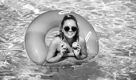 Summer Vacation. Enjoying suntan. Woman in swimsuit on inflatable circle in the swimming pool headphones music.の写真素材