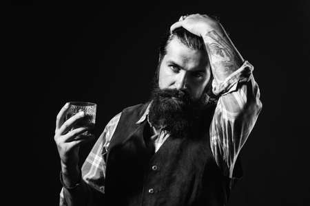 Bearded businessman in elegant suit with glass of whiskey. Sipping whiskey. Bearded handsome man holding glass of whiskey.の写真素材