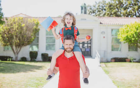 Father and son piggyback ride trough school park.の写真素材