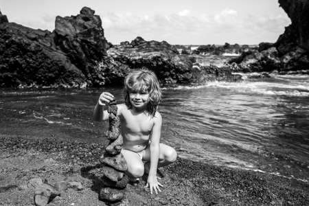 Kid making pebbles are piled on a volcanic rock by the sea. Zen concept.の写真素材