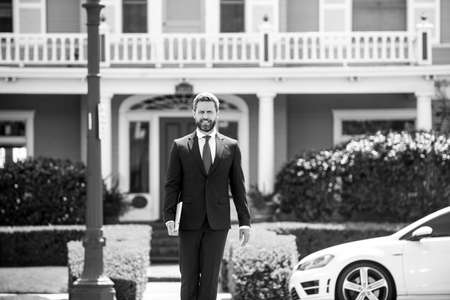 Real estate. Agent ready to sell home. Businessman standing outside a modern house.