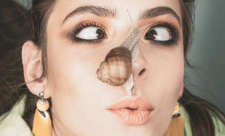 Massage with snail. Skincare repairing. Healing mucus. Having fun with adorable snail. Cosmetics and snail mucus. Cosmetology beauty procedure. Girl fashionable makeup face and cute snail. Skin careの写真素材