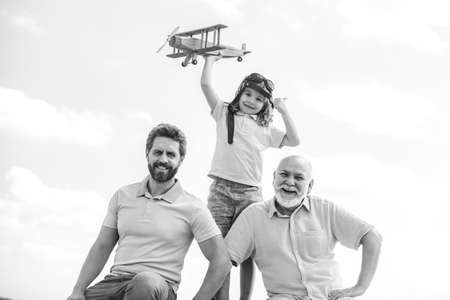 Three generations of men together, portrait of smiling son, father and grandfather with a toy airplane. Child boy playing with plane and dreaming future. Start, creativity startup concept.の写真素材