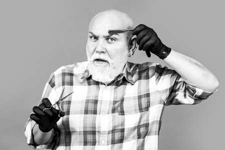 Mature barber with scissors and razor. Vintage barbershop, shaving.