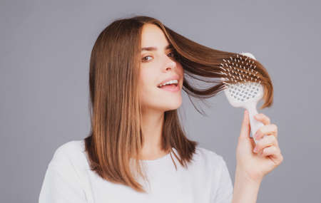 Attractive woman combing hair. Beautiful girl combs hair. Haircare concept.の写真素材