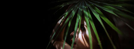 Spring woman face for banner. Girl in the leaves of the palm trees.Beautiful young woman with...