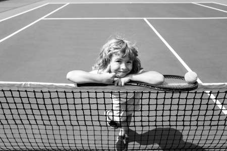 Child boy with tennis racket and ball on tennis court outdoor. Sport exercise for kids. Summer activities for children.の写真素材