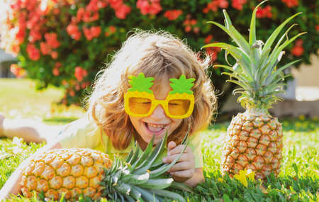 Portrait of little kid outdoors in summer. Smiling cute funny boy holding a pineapple.の写真素材