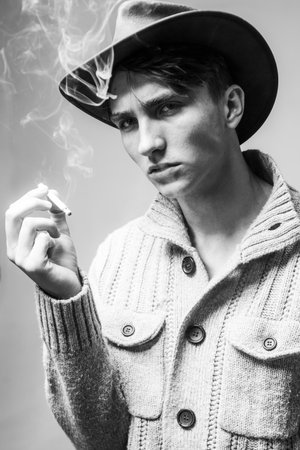 Close up young man smoking a cigarette. Man with cigar. Handsome man wear cowboy hat.の写真素材